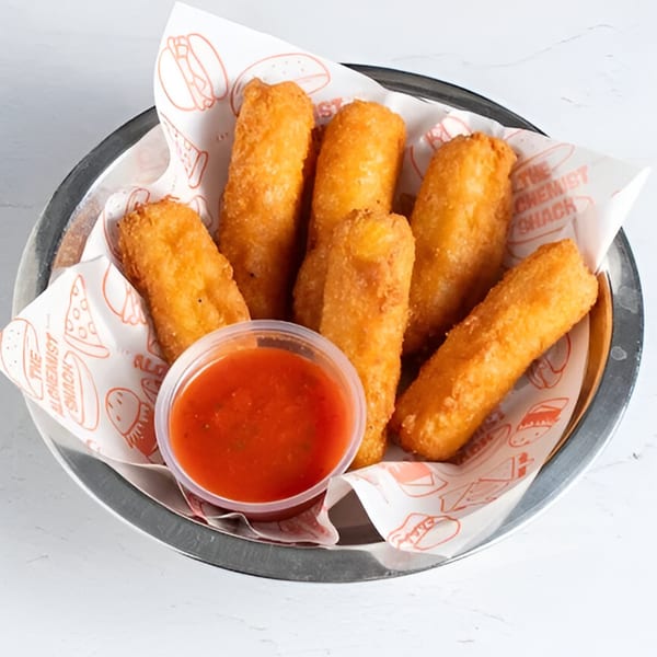 A metal basket filled with golden-brown mozzarella sticks and a side of red marinara sauce.